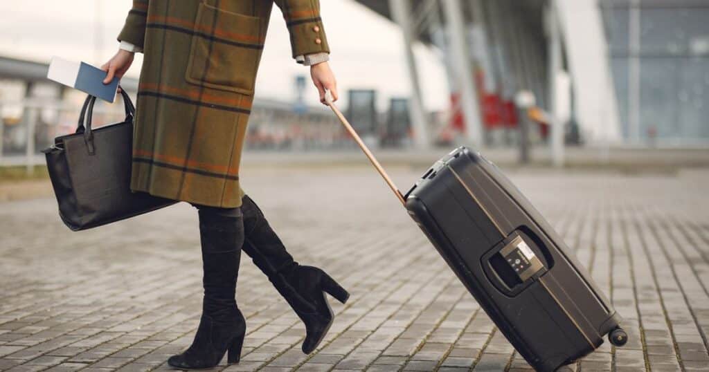 Femme tirant une valise rigide a roulettes